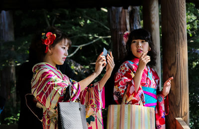 Portrait of smiling young woman holding smart phone