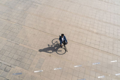 Man riding bicycle on promenade while looking up during sunny day