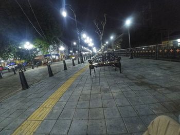 Illuminated street lights on footpath in city at night