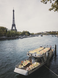 Dreamy image of tied journey boat with empty seats on river seine with eiffel tower in background