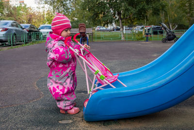 Low section of woman with pink slide in playground