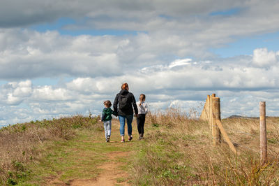 Rear view of friends on land against sky