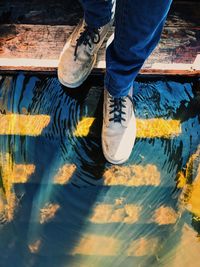 Low section of man standing on steps over lake