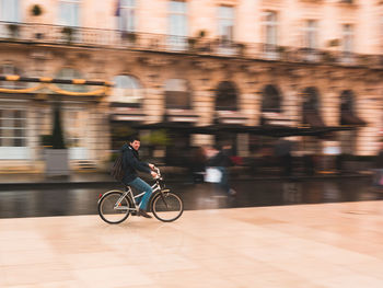 Rear view of man riding bicycle on street in city