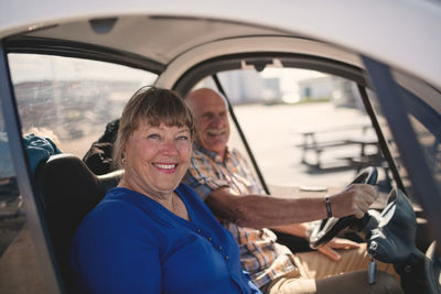 Portrait of smiling senior woman and man enjoying car ride on sunny day