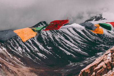 Close-up of multi colored flags on mountain against sky