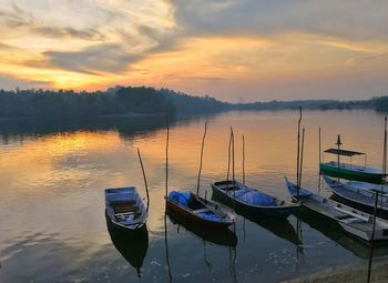 Boats moored in lake against sky during sunset