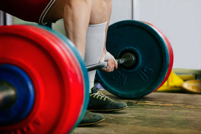 Low section of woman exercising with dumbbell on hardwood floor