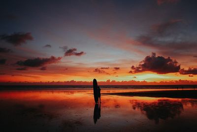 Silhouette man on beach against sky during sunset