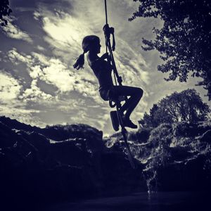 Low angle view of silhouette man jumping against sky