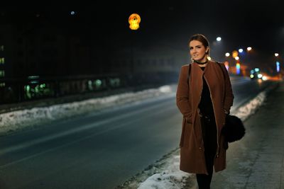 Young woman on city street at night