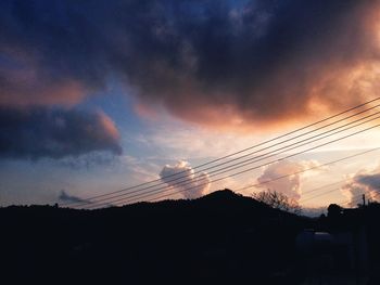 Low angle view of silhouette cables against sky during sunset