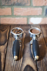 High angle view of coffee in containers on table against brick wall in cafe