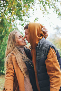 Smiling couple standing against tree