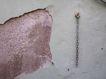 Chain hanging on damaged wall