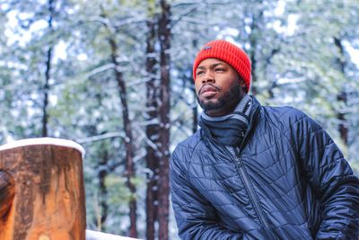 Bearded young man wearing warm clothing in forest during winter