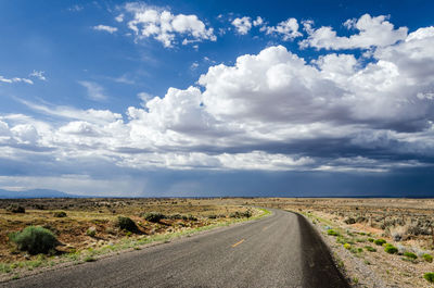 Road amidst field against sky