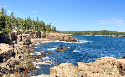 Scenic view of rocks on beach against blue sky