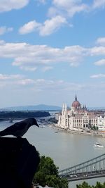 City at waterfront against cloudy sky