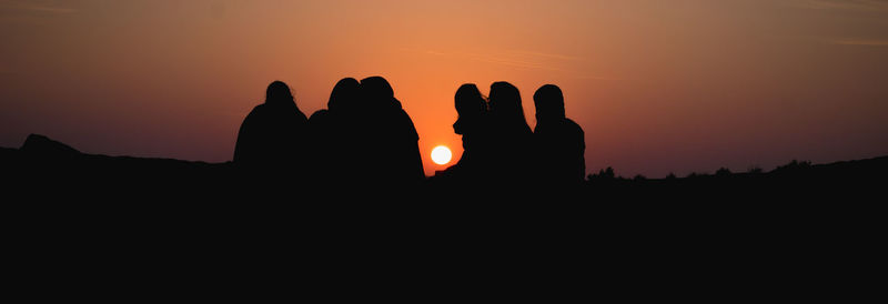 Panoramic shot of silhouette friends against clear sky during sunset