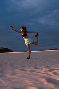 Woman making yoga pose at sunset in sand dunes