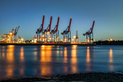 Cranes at commercial dock against sky at night