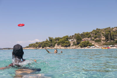 Happy young couple playing with a plastic disc in the sea. travel, vacation and fun