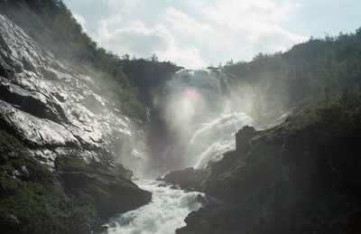 Scenic view of waterfall in forest against sky