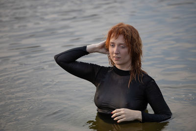 Portrait of young woman standing against sea