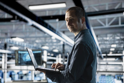 Young man using mobile phone while standing in office
