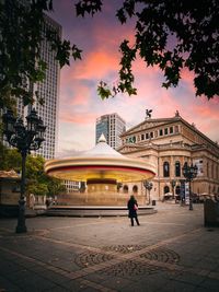 People at historic building against sky during sunset