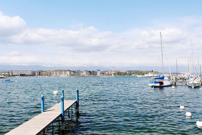 Sailboats moored in sea against sky