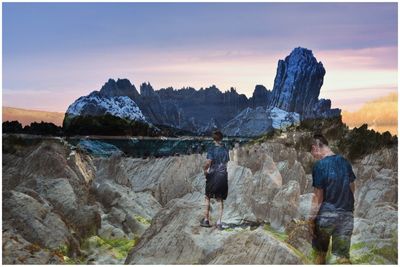 Rear view of people looking at mountains against sky