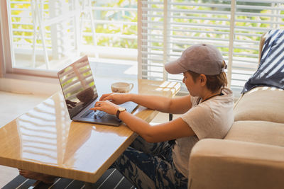 Young woman using laptop while sitting at cafe