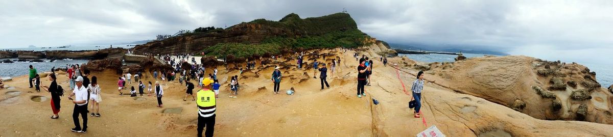 Panoramic view of people on beach against sky