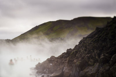 People in hot spring against mountain