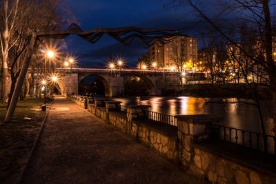 Illuminated bridge over river against sky at night