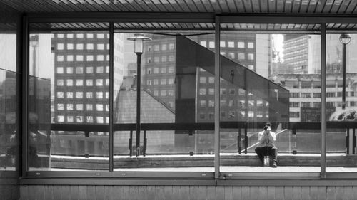 Rear view of man walking by modern building in city