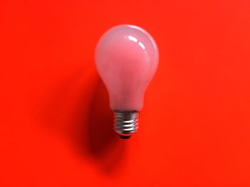 Directly above view of light bulb on red background