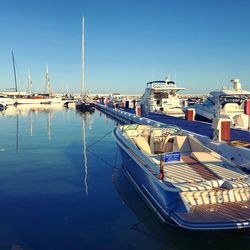 Sailboats moored at harbor against clear blue sky