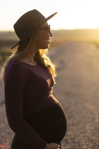 Side view of woman wearing hat standing on land