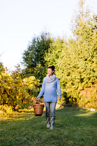 Happy beautiful woman walking with basket at orchard