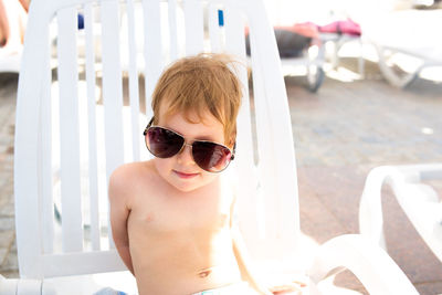 Small child in panama hat plays in the summer on sunny day near swimming pool