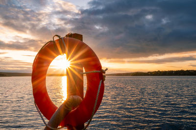 Lifebelt hanging on wooden post at lake wannsee during sunset