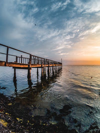 Pier over sea against sky during sunset