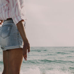 Midsection of man standing by sea against sky