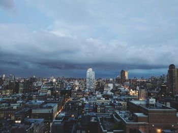 Illuminated cityscape against cloudy sky