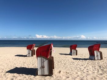 Hooded chairs on beach against sky