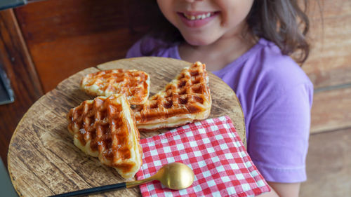 Midsection of girl holding croffle on table