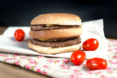 Hamburger with tomatoes on paper over table